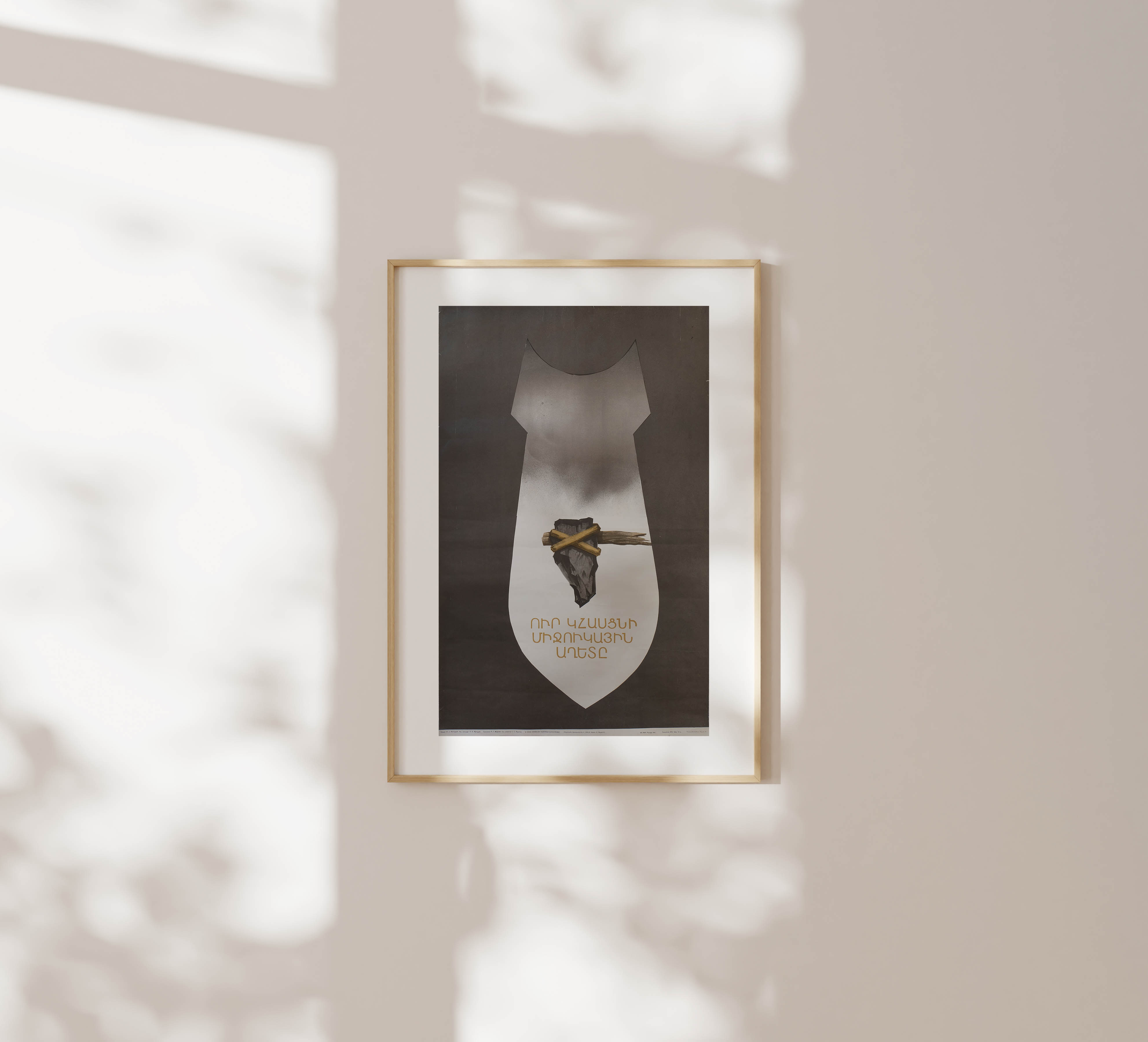 Framed anti-nuclear poster hanging on a beige wall in soft natural light with delicate leaf shadows cast across the surface.